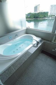 Hotel Luandon Shirahama في شيراهاما: حوض استحمام في حمام مع نافذة كبيرة