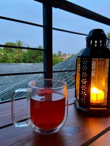 a cup of tea sitting on a table next to a lantern at Ski Villa, Modern Calm and Cozy Lakeside Villa Rooms Anuradhapura City Sri Lanka in Anuradhapura