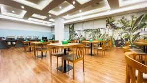un restaurant avec des tables et des chaises en bois et une fresque murale. dans l'établissement Barbara Hotel, Changlong Dashi Subway Station, Panyu District, Guangzhou, à Canton