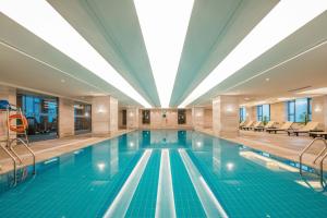 une grande piscine avec un grand plafond dans l'établissement Happiness Hotel, à Changzhou