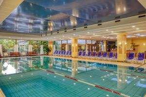 a swimming pool with blue chairs in a building at Ensana Grand Margaret Island in Budapest