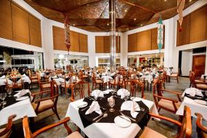 a dining room with white tables and wooden chairs at Mandara Rosen Yala, Kataragama in Kataragama