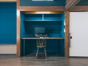a desk with a chair in a room with blue walls at ワイナリーや酒蔵巡りなどにおすすめの宿 小諸市 築100年の古民家 Chojuro -長寿楼- in Komoro