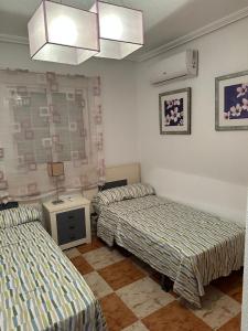 a room with two beds and a table with a lamp at Playa Golf II Campoamor in Los Dolses