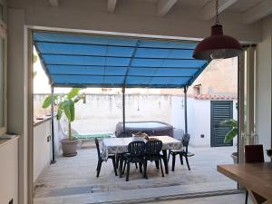 a patio with a table and chairs and a blue shade at Casa Lauretta - terrazza con idromassaggio - garage wifi e bici gratuite in Lecce