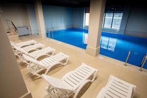 a row of white chairs in front of a pool at Solis Residence Aparthotel in Batumi