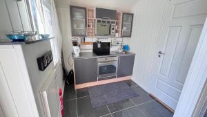 a small kitchen with a stove and a microwave at Litla Hyttå, Mosterhamn Bømlo in Mosterhamn