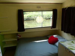 ein kleines Schlafzimmer mit einem Bett mit Fenster in der Unterkunft nuitée insolite aux berges d'un canal tranquille 