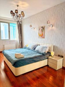 a bedroom with a bed with blue sheets and a chandelier at Cozy Apart in Center in Baku