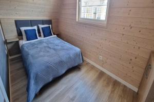 a bedroom with a bed with blue sheets and a window at Comfortable holiday homes, Sarbinowo in Sarbinowo