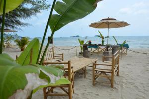 a wooden table and chairs on a beach with the ocean at Tides Signature Koh Chang in Ko Chang +73 photos