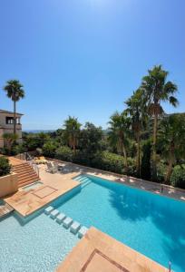 ein großer Swimmingpool mit Palmen im Hintergrund in der Unterkunft Villa 49 Hameau des Greens in Sainte-Maxime