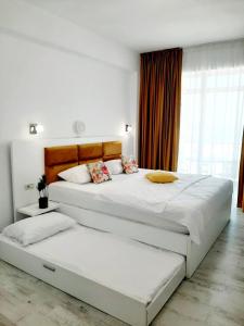 une chambre avec deux lits et une grande fenêtre dans l'établissement Tasos - Rooms with see View, à Eforie Nord