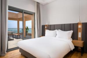 ein Schlafzimmer mit einem großen weißen Bett und einem Balkon in der Unterkunft Radisson Residences Taghazout Bay in Agadir + 65 Fotos