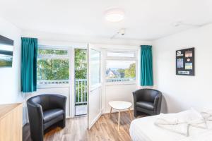 a room with two chairs and a bed and a window at North Devon Getaways in Ilfracombe