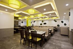 a dining room with tables and chairs and lights at Hotel Sifat International in Surat