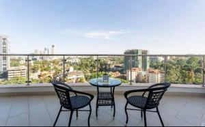 a table and chairs on a balcony with a view at Skyline Aramis Apartment Westlands,2bedroom,2baths in Nairobi