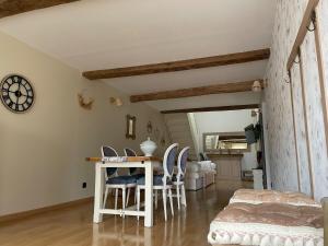 a living room with a table and chairs and a clock at Petit cocon à 5 min de Sedan in Sedan