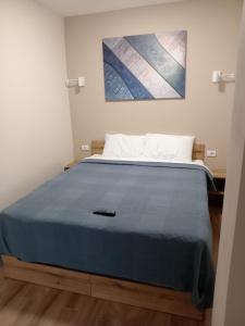 a bed in a room with a blue blanket on it at Hello One 2 Apartman in Šabac