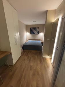 ein Schlafzimmer mit einem Bett in einem Zimmer mit Holzböden in der Unterkunft Hello One 2 Apartman in Šabac