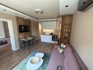 a living room with a purple couch and a kitchen at Hello One 2 Apartman in Šabac