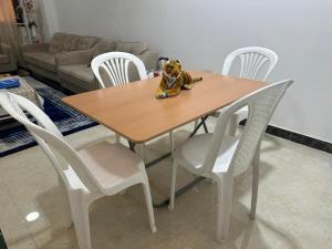 a wooden table with white chairs and a dog toy on it at Ghala apartment Near airport free Wifi in Muscat +1 photo