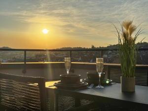a table with two glasses of wine on a balcony with the sunset at Zentrale Penthouse Suiten mit Goldstadtblick in Pforzheim