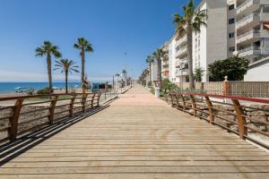 Un paseo marítimo a lo largo de la playa con palmeras y edificios. en Nordik Apartments Village - Rincón "Brevik", en Rincón de la Victoria