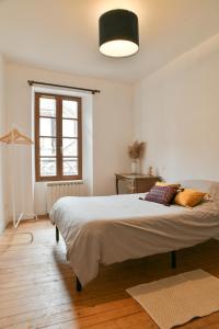 Charmant T4 Centre-ville, Lacs et Montagnes في Le Pont-de-Beauvoisin: غرفة نوم بيضاء مع سرير كبير ونافذة