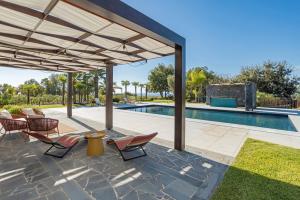a patio with chairs and a swimming pool at Villa White Oleander Etna and Pool in Calatabiano