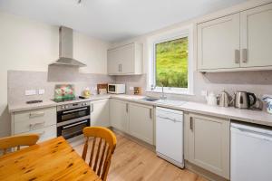a kitchen with white cabinets and a wooden table at Charming 2-Bed Cottage on Tranquil Raera Farm in Kilninver