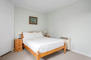 a white bedroom with a bed and a radiator at Charming 2-Bed Cottage on Tranquil Raera Farm in Kilninver