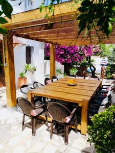 a wooden table and chairs on a patio with flowers at Finca Craig, Spacious Farmhouse with amazing garden and private heated pool in Rótova