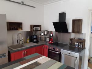 a kitchen with red cabinets and a sink and appliances at Le marché couvert in Étretat