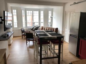 Una cocina con una mesa con sillas y un refrigerador. en Le marché couvert, en Étretat