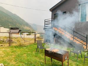 a grill with smoke coming out of it next to a house at Hotel & Cottages Mountain View in Kazbegi