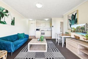 Una sala de estar con un sofá azul y una mesa. en Inner-City 1-Bed with Pool & Spa, en Brisbane