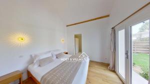 Un dormitorio con una cama y una ventana grande. en Host Villas CASA SOLEADA Tosse, en Tosse