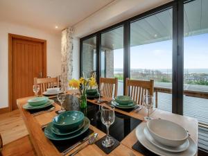 a dining room with a table with plates and wine glasses at Bodwennol - a stunning house! in Aberdyfi