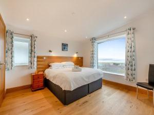 a bedroom with a large bed and two windows at Bodwennol - a stunning house! in Aberdyfi