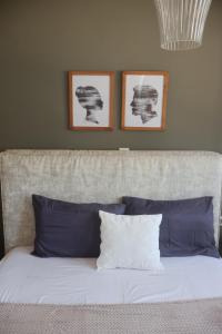 a bed with blue pillows and two pictures on the wall at Athenean Coastal Getaway in Athens