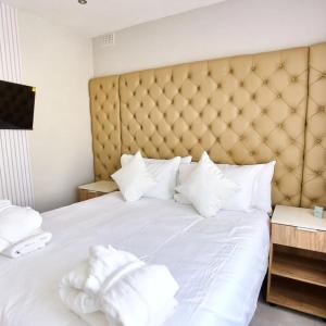 a large white bed with white pillows on it at The Mendel Boutique Residency in Harare +1 photo