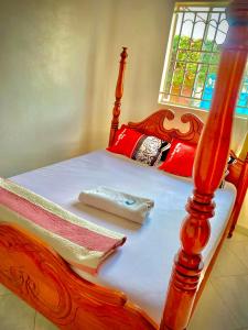 a bed with a wooden frame with a towel on it at Jacobin Guest House & Cottages in Namulanda