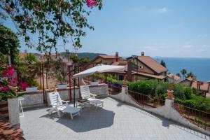 a patio with chairs and an umbrella and a house at Sunrise Place Casa Vacanze in Praia a Mare