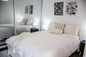 een slaapkamer met een groot wit bed en spiegels bij Cozy City House in the Heart of Paddington in Sydney