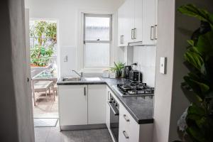 een witte keuken met een spoelbak en een fornuis bij Cozy City House in the Heart of Paddington in Sydney