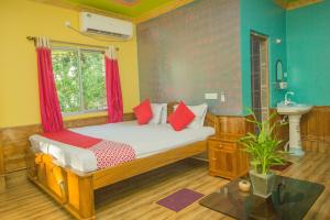 a bedroom with a bed with red pillows and a sink at Hotel O Sandhana Homestay in Alīpur Duār