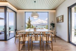 a dining room with a table and chairs and a large window at Horizon Villa Luxurious Lakefront Retreat in Široka