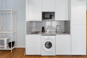 a white kitchen with a washing machine and a sink at GuestReady – Urban comfort in Vila Nova de Gaia in Vila Nova de Gaia