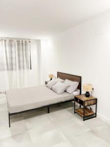 a white bedroom with a bed and a table at Diyenn Burriana alojamiento y placer in Burriana